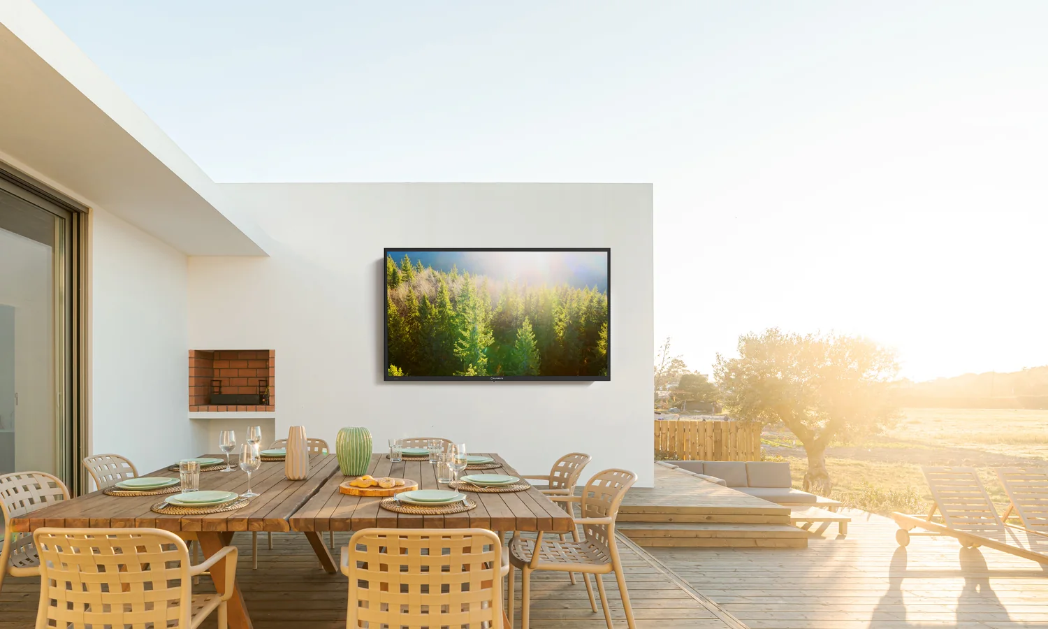 A television mounted under a pergola above a deck dining table