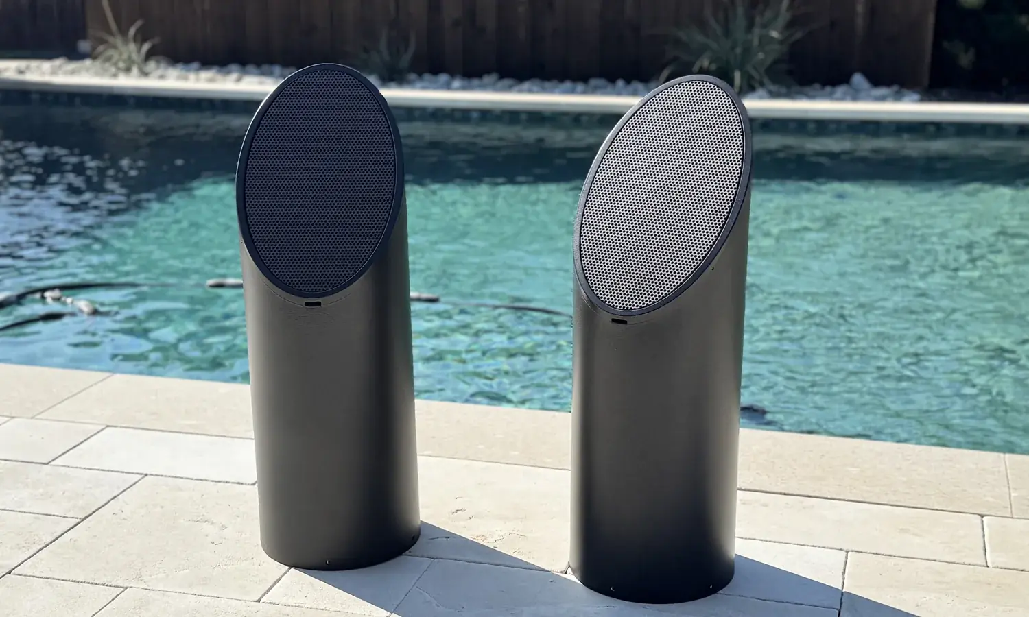 Two Coastal Source Ellipse bollard speakers on the coping of a pool