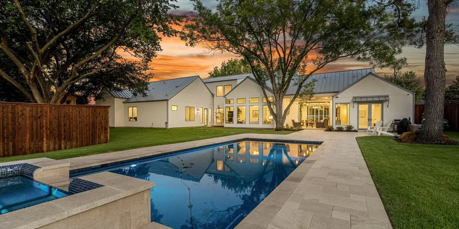 The rear of a custom residence at dusk, pool and terrace lit, with no speaker, keypad or fixture visible anywhere on the elevation